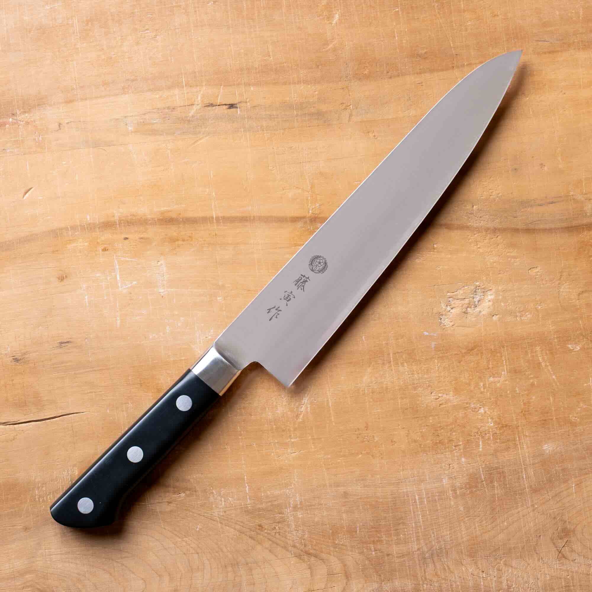 Chef's knife with a black handle on a wooden cutting board