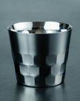 Metallic silver cup with geometric pattern on a dark gray background