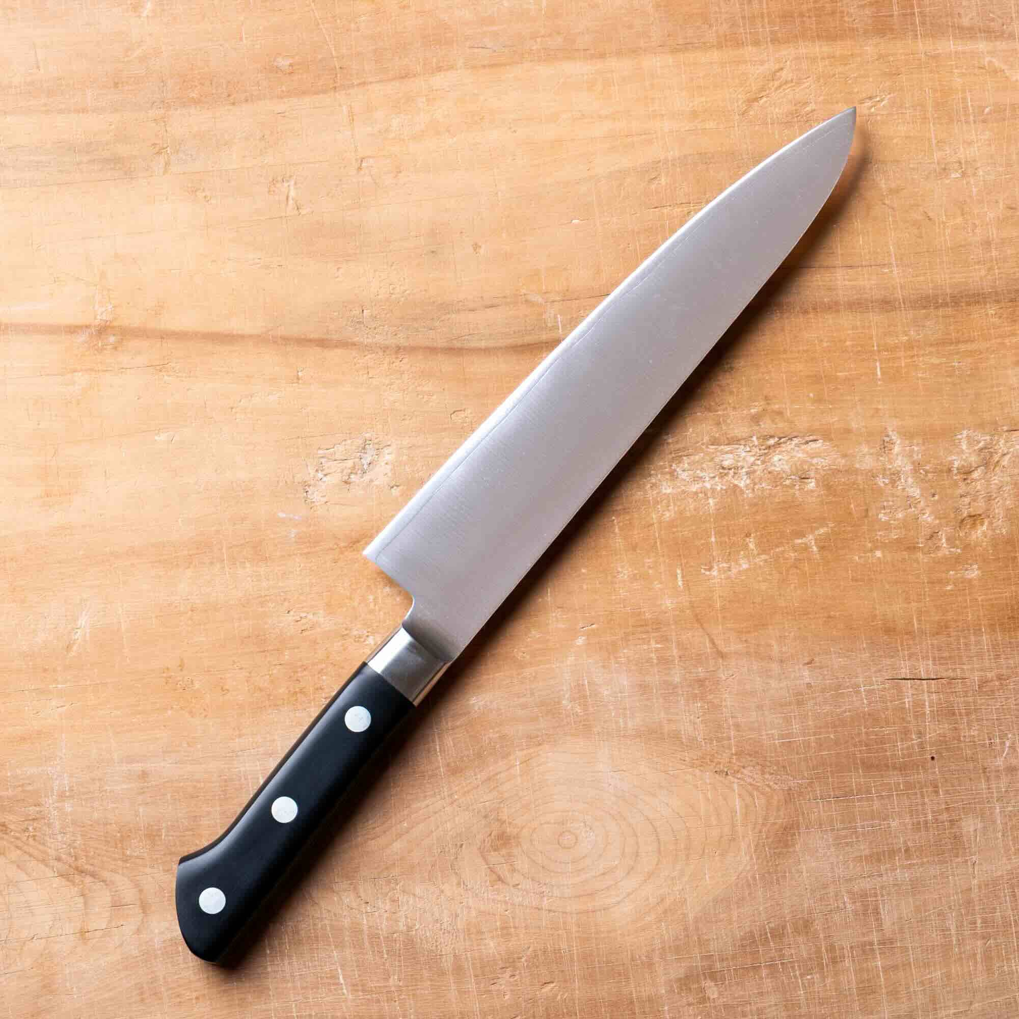 Chef's knife with a black handle on a wooden cutting board